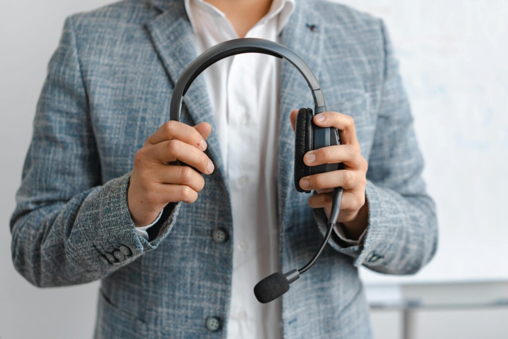 Person in Blue Blazer Holding a Black Headphones